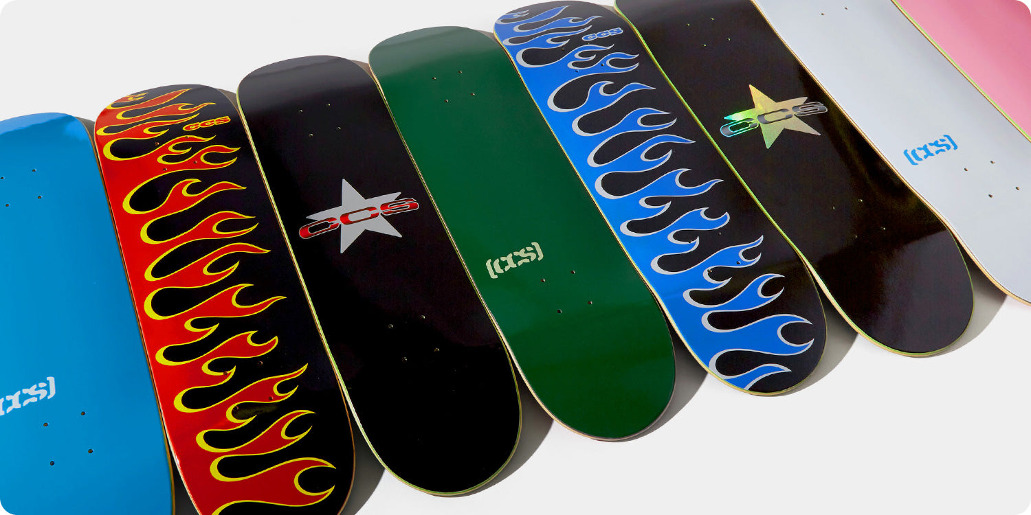 Collection of skateboard decks with various designs and branding on a white background