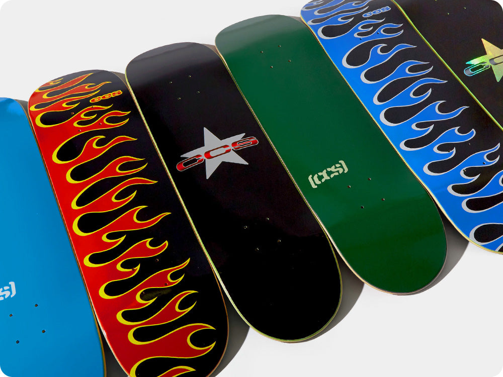 Collection of skateboard decks with various designs and branding on a white background